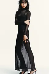 Vestido largo negro de malla semitransparente con cuello alto y mangas largas. Incluye un body interior negro a tono.