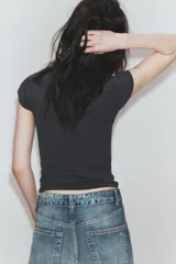 Camiseta slim fit color gris oscuro, con cuello redondo y manga sisa caída. Presenta un texto blanco en el delantero que dice "Main character Role".