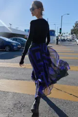 Falda midi de corte asimétrico con diseño cruzado en el delantero y aberturas. Presenta un estampado geométrico en tonos azul, negro y beige, con forro interior y cierre trasero con cremallera oculta.