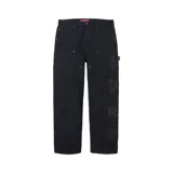 Pantalón Supreme estilo painter de corte regular, color negro, con apliques de cuero en tipografía gótica en la pierna izquierda y presillas para cinturón.