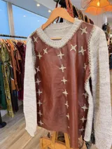 Sweater de diseño artesanal con frente de cuero marrón y mangas y espalda tejidas en lana color beige. Presenta detalles de bordados a mano en forma de cruz a lo largo de las costuras laterales y el escote.