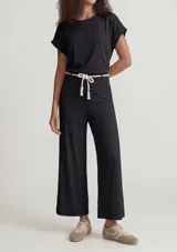 Pantalón acanalado de color negro, de corte recto y holgado, con cintura elastizada y cordón decorativo en tono crudo con cuentas de madera en los extremos.