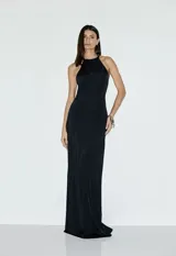 Vestido largo negro de satén con escote halter y diseño fluido, con detalle de accesorio escultórico en la espalda.