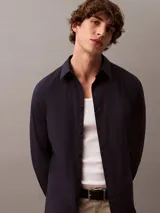 Camisa de manga larga Calvin Klein con corte slim, cuello clásico estructurado y cierre frontal con botones a tono. Presenta un diseño minimalista con monograma bordado en el pecho.