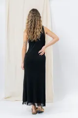 Vestido midi de tejido tipo seda con caída fluida, escote redondo y sin mangas. Presenta un diseño minimalista con detalle de flecos en el ruedo.