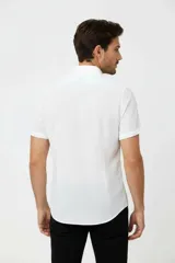 Camisa de algodón blanca de manga corta, con cuello camisero y cierre frontal de botones.