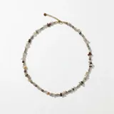 Collar corto compuesto por escallas de piedras naturales en tonos neutros, intercaladas con pequeñas cuentas doradas. Cuenta con cierre de mosquetón y cadena de alargue.