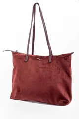 Bolso tipo tote de gran tamaño en color bordó, confeccionado en material sintético con textura de gamuza. Cuenta con cierre superior, correas largas de hombro en tono marrón oscuro y una placa metálica decorativa en el frente.