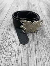 Cinto negro de cuero sintético con hebilla plateada en forma de mariposa.