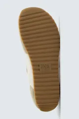Zapatilla deportiva estilo barefoot, color marrón, con diseño de puntera ancha y redondeada. Confeccionada en una combinación de materiales textiles y detalles en serraje. Cuenta con suela fina de goma flexible y cordones en color crema.