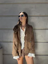 Campera marrón de gamuza sintética con cierre frontal, cuello camisero y bolsillos con solapa en el pecho.