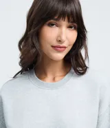 Buzo femenino de cuello redondo y manga larga, confeccionado en tejido de algodón con felpa. Presenta un diseño básico sin estampado, con puños y ruedo ajustados en tejido rib.