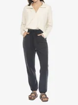 Sweater de manga larga color crema, con cuello tipo Johnny (cuello polo abierto en V) y puños y ruedo con terminación deshilachada.