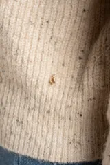 Cardigan de punto con cierre frontal completo, cuello alto y diseño de canalé. Presenta un acabado jaspeado en tono beige.