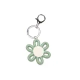 Llavero con dije en forma de flor, elaborado con tejido de hilo en colores verde y blanco, con argolla y gancho metálico plateado.