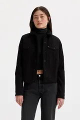 Campera trucker negra de denim con cuello de sherpa, cierre frontal con botones metálicos, bolsillos con solapa abotonada en el pecho y bolsillos laterales. Corte recto y puños abotonados.