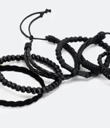 Kit de seis pulseras masculinas de color negro con distintos diseños, incluyendo modelos trenzados con cierre ajustable y modelos de cuentas de madera y vidrio.