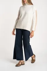 Polera de punto con diseño oversize, cuello alto y mangas largas con paneles laterales en contraste. Presenta un tejido jaspeado con motas multicolores y detalles de lurex.