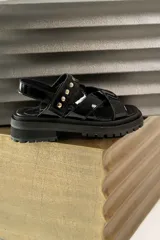 Sandalias de cuero marrón con textura de cocodrilo, diseño de tiras cruzadas con tachas metálicas plateadas y suela track negra de plataforma.