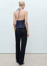Pantalón de vestir negro de corte recto y tiro bajo, con pinzas frontales, bolsillos laterales y cierre oculto con botón, gancho y cremallera.