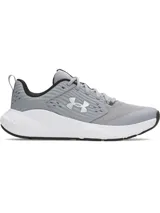 Championes de entrenamiento Under Armour modelo Charged Commit TR 4, color gris con detalles en blanco y negro. Presentan una parte superior de malla transpirable con refuerzos laterales texturizados y el logo de la marca en el costado. Cuentan con mediasuela Charged Cushioning para amortiguación y suela de goma con ranuras de flexión.