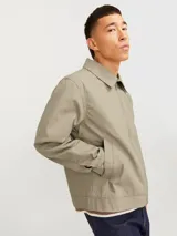 Campera estilo worker de corte recto, confeccionada en tejido plano Oxford de algodón color verde grisáceo. Presenta cuello clásico, cierre frontal completo con cremallera metálica, mangas largas con puños abotonados y bolsillos laterales integrados.