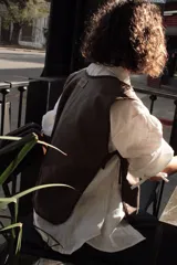 Chaleco marrón de paño fino 100% lana, con tiras de ajuste laterales y frontales.