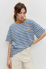Remera de manga corta con diseño a rayas horizontales azules y blancas, cuello redondo en color tostado y parche bordado en el pecho.