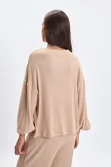 Remera de manga larga confeccionada en tejido rib, color beige, con cuello redondo y diseño de mangas anchas con corte holgado.