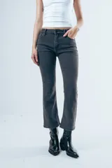 Jean de corte bootcut y tiro medio, color gris oscuro desgastado. Presenta un diseño de pierna recta que se ensancha ligeramente hacia el ruedo, con cierre frontal y bolsillos clásicos.