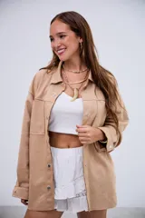 Sobrecamisa de gamuza en color beige, con corte oversize, cierre frontal con botones metálicos a presión, bolsillos frontales y mangas largas con puños abotonados.