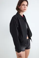 Campera bomber color beige con cuello solapa, confeccionada en 100% algodón, con cierre frontal con cremallera y acabado elástico en el bajo.