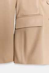 Blazer cruzado de efecto piel color bordó, con solapas de muesca, mangas largas y bolsillos con solapa en la parte delantera. Cierre frontal con botones a tono.