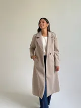 Tapado largo de paño en color beige, con solapas anchas, cierre frontal de un botón y diseño estructurado.