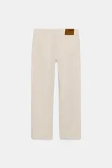 Jeans de tiro medio con corte slim leg, confeccionados en denim color beige. Presentan cintura con trabillas, diseño clásico de cinco bolsillos y cierre frontal con cremallera y botón metálico.