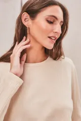 Remera de manga larga color terracota, con textura acanalada y cuello redondo.