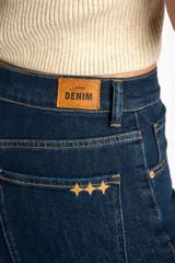 Jean de corte wide leg y tiro medio, confeccionado en denim de algodón. Presenta costuras verticales decorativas a lo largo de las piernas y cierre frontal con botón y cremallera.
