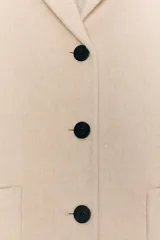 Abrigo corto de Zara confeccionado en hilatura con lana, con cuello solapa, manga larga, bolsillos de plastrón en el delantero y cierre frontal con botones.
