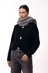 Saco de tejido de punto grueso en color negro, con cuello redondo y cierre frontal mediante tres botones metálicos grandes de acabado texturizado. Presenta bolsillos delanteros y mangas largas con puños ajustados.