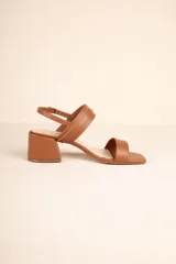 Sandalia de mujer color marrón, con taco ancho y tiras de símil cuero, incluyendo una tira ancha en la parte delantera y una tira ajustable con hebilla metálica alrededor del tobillo.