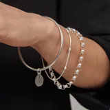 Brazalete tipo esclava de alambre redondo en plata 925, con dije de medalla circular colgante.