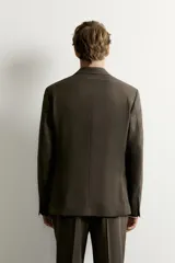 Blazer slim fit de corte sastrero en color verde oscuro, con cuello de solapa de muesca, bolsillos con solapa en la cadera y cierre frontal de botones.