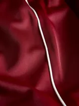 Pantalón deportivo de corte relajado y tiro medio, color bordó, con pretina elástica y detalle de franja lateral blanca.