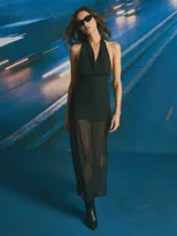 Vestido largo negro con escote drapeado tipo halter y falda transparente.