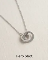 Collar de acero con cadena fina y dos dijes circulares entrelazados, uno de ellos con incrustaciones de circonias.