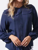 Blusa azul marino de Zac & Rachel con cuello a la base, abertura central con botones y detalle de broderie en el frente. Tiene mangas largas con terminación elastizada.