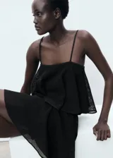 Vestido corto negro de punto fino, sin mangas, con tirantes finos, escote cuadrado y maxi volante superpuesto en el pecho con diseño evasé.