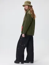 Campera tejida de punto grueso con diseño multicolor. Presenta cuello en contraste de color verde, cuerpo en tono beige con textura trenzada, bolsillos delanteros con apliques en nylon color marrón y bordó, y detalles en nylon en los hombros. Cuenta con cierre frontal de botones y forro interno.