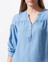 Blusa de manga tres cuartos color celeste claro, confeccionada en lyocell, con escote en V y detalle de frunces en el canesú y puños.