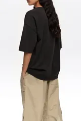 Remera de corte recto y diseño oversize, confeccionada en algodón orgánico. Presenta escote redondo, mangas cortas y estampa frontal en blanco y negro con la ilustración de bailarinas y la inscripción "Bimba y Lola Dancers".